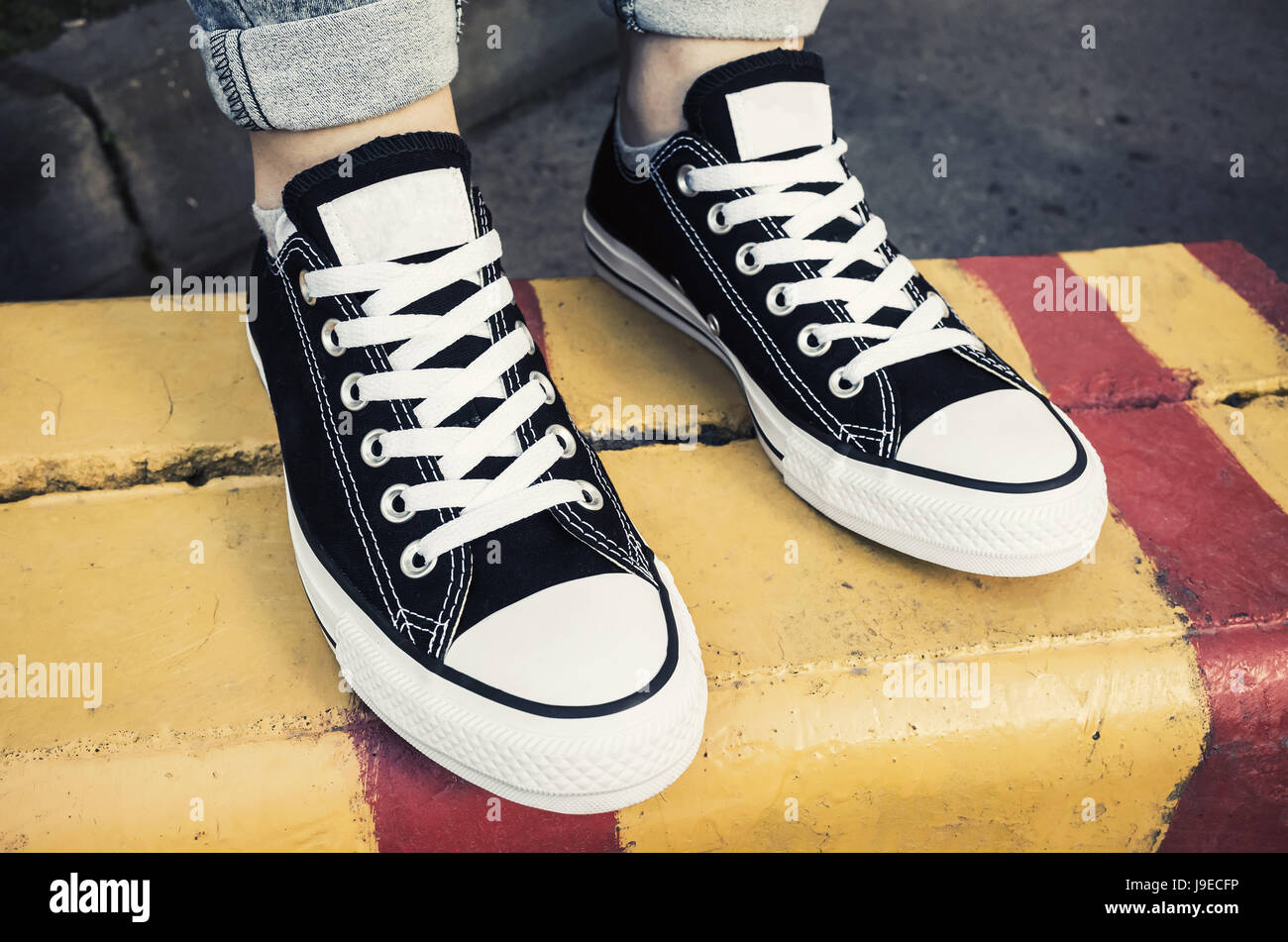 Schwarz / weiß neue Turnschuhe, Teenager Füße auf städtische Straße Grenze stehen. Nahaufnahme Foto mit selektiven Fokus Stockfoto