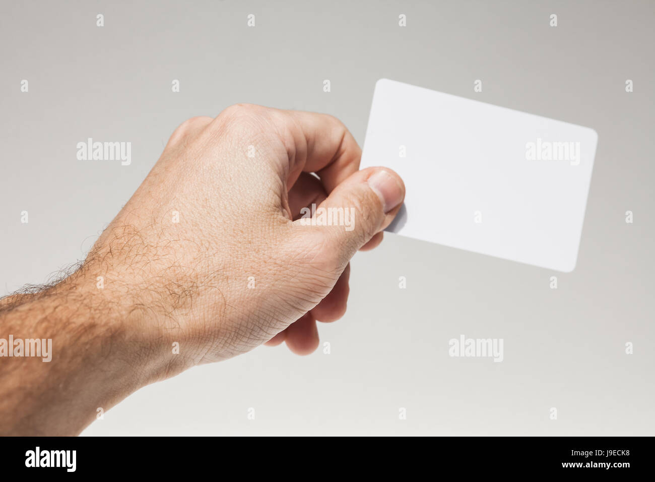 Männliche Hand hält weiße leere Karte über grauen Hintergrund, Nahaufnahme Foto studio Stockfoto