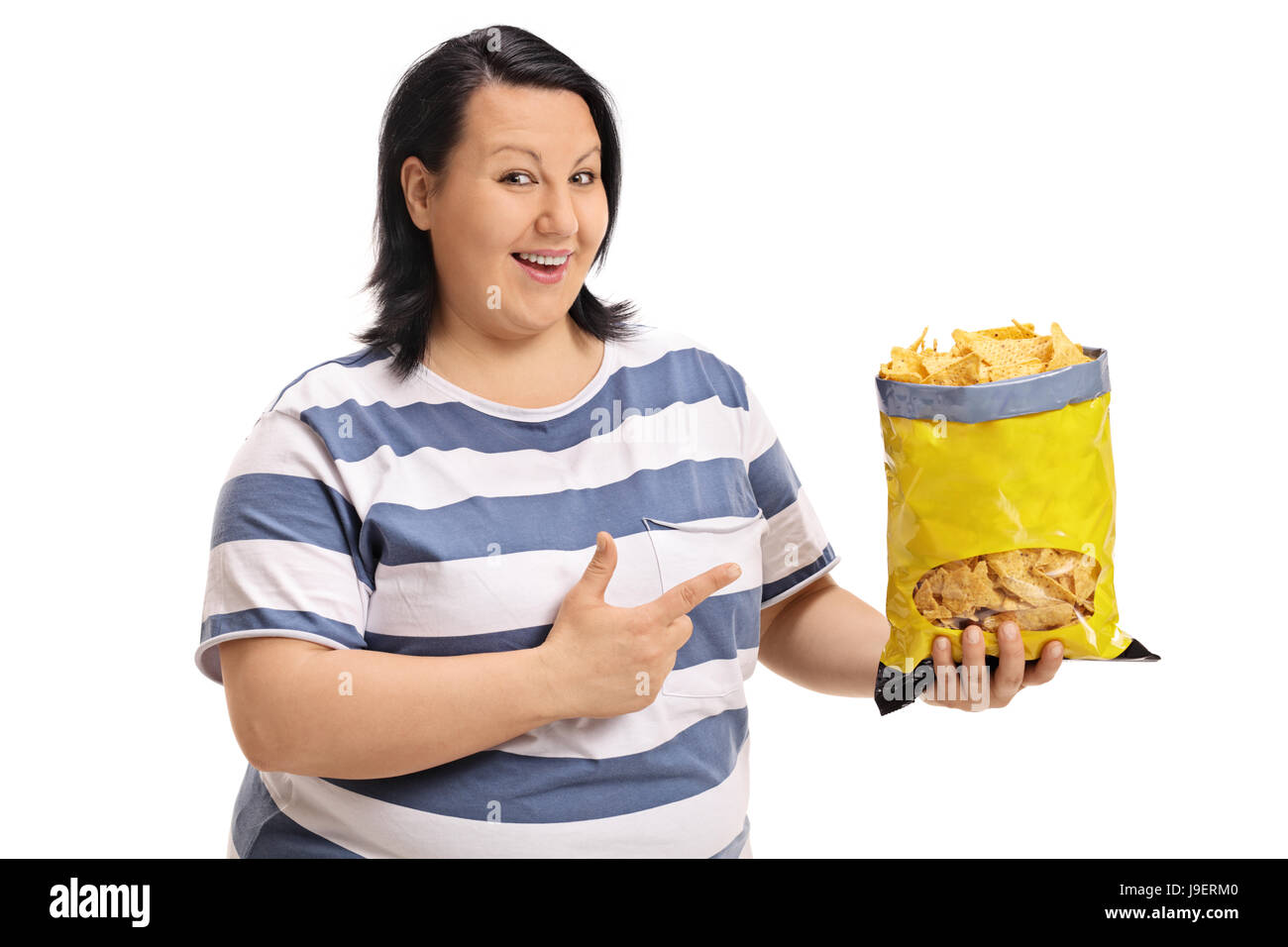 Glücklich übergewichtige Frau hält einen Beutel der Späne und zeigt auf weißem Hintergrund isoliert Stockfoto