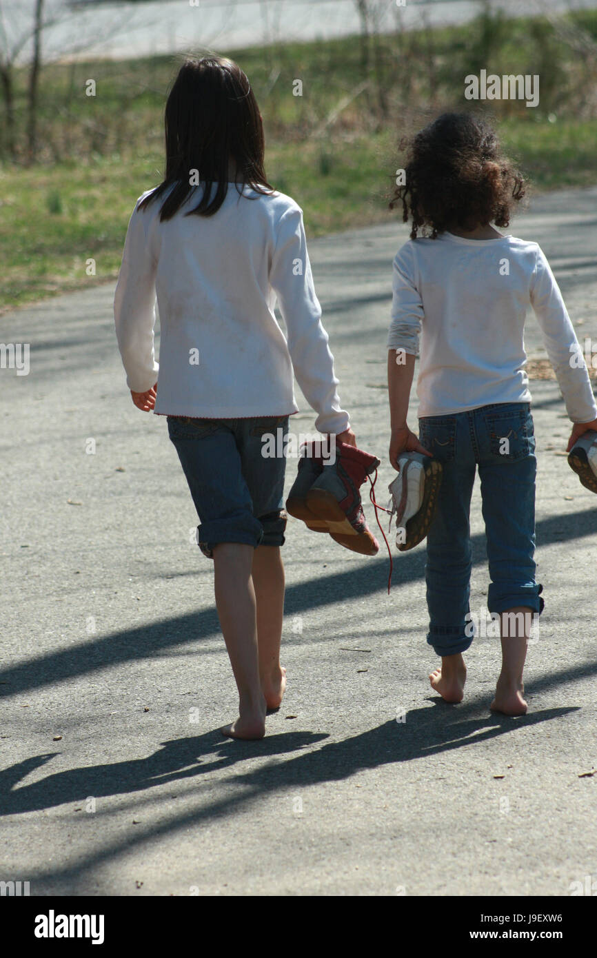 Zwei kleine Mädchen gehen barfuß auf der Gasse Stockfoto