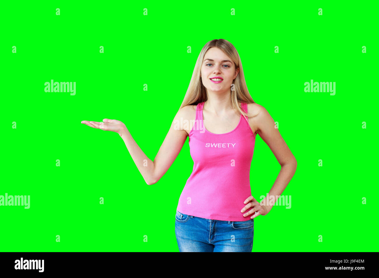 Frau, die Ihr Produkt oder Ihre Botschaft lächelt glücklich isoliert auf green-Screen Chroma Key Hintergrund. Schöne Mädchen in rosa Tanktop zeigt offenen hand Stockfoto