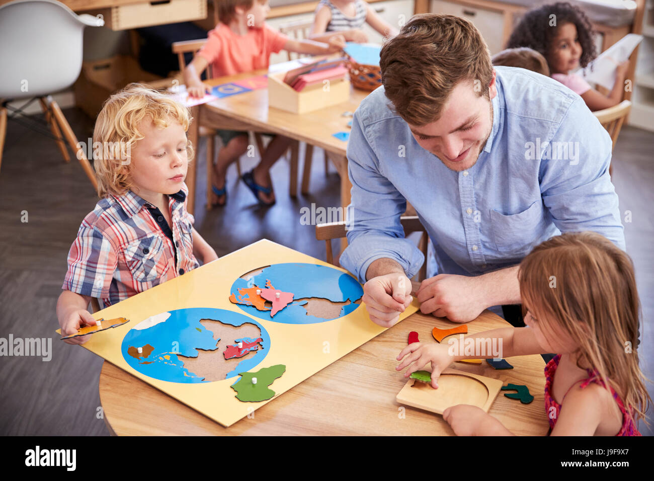 Lehrer und Schüler mit Formen aus Holz In der Montessori-Schule Stockfoto