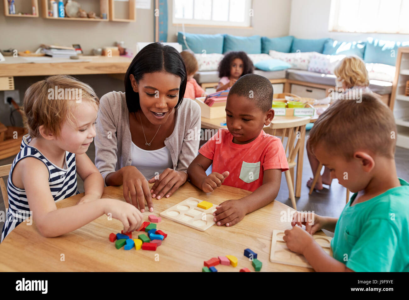 Lehrer und Schüler mit Formen aus Holz In der Montessori-Schule Stockfoto