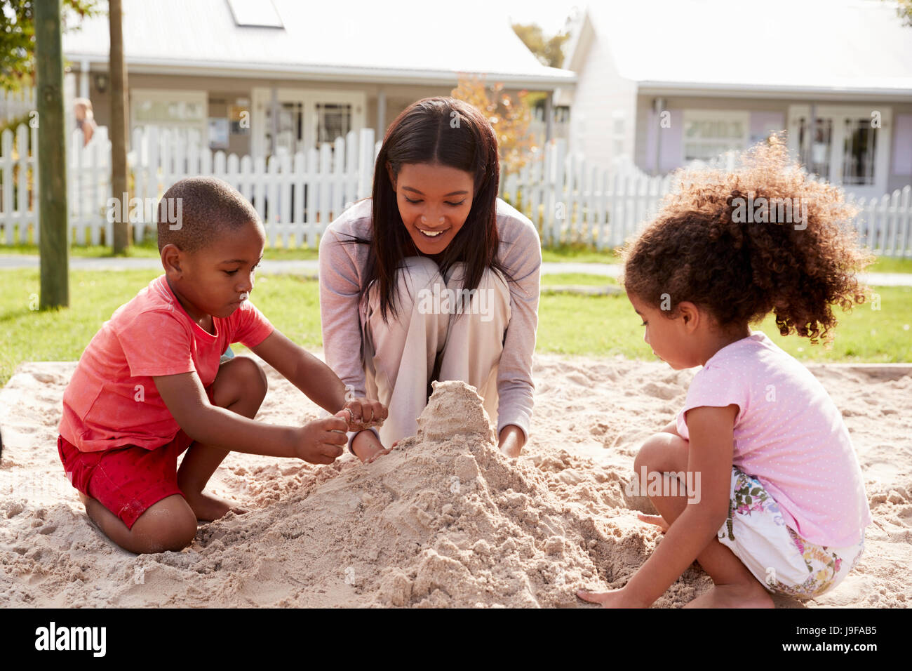 Lehrer an der Montessori-Schule mit Kindern im Sandkasten spielen Stockfoto