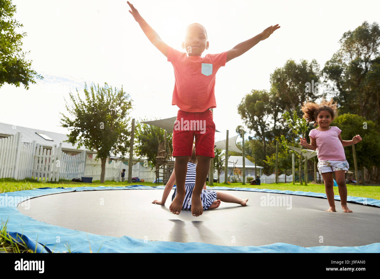 Kinder in der Montessori Schule Spaß am Outdoor-Trampolin Stockfoto