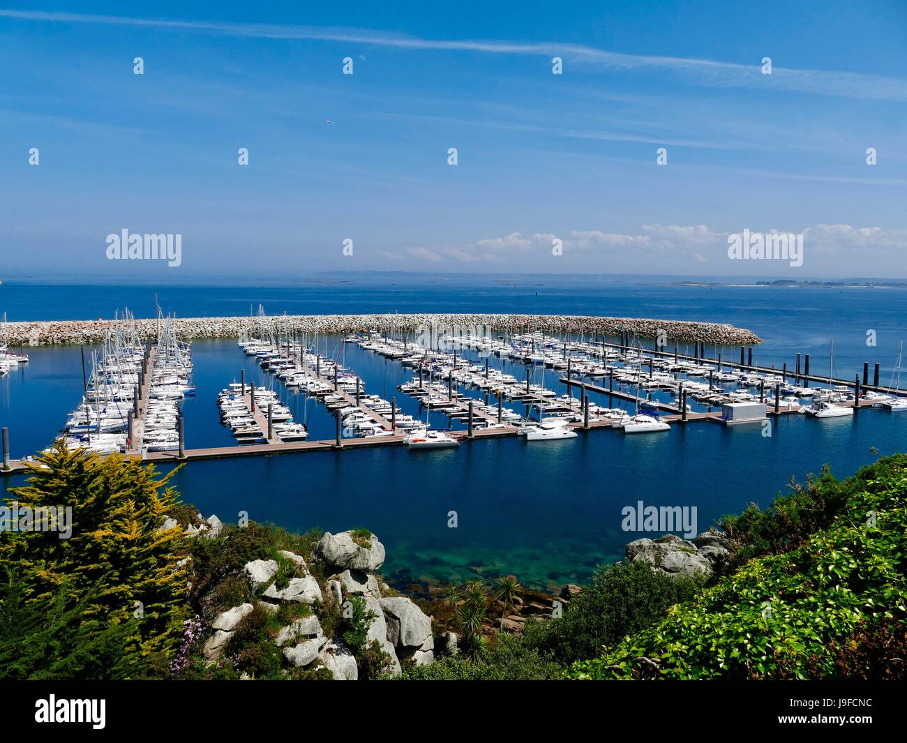 Sportboote im Hafen in Port du Blascon mit Granit Anlegesteg und Bucht von Morlaix im Hintergrund. Roscoff, Bretagne, Frankreich. Stockfoto