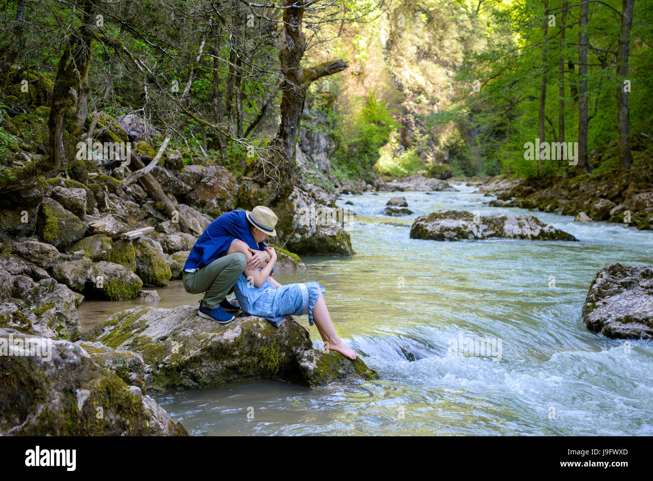 Ein Mädchen und ein Junge sind durch den Fluss umarmt. Stockfoto