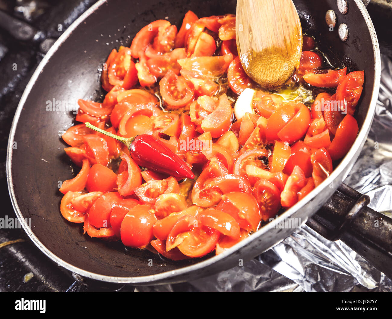 frische Tomaten Cookig in einer Pfanne mit Knoblauch und scharfe Paprika Stockfoto