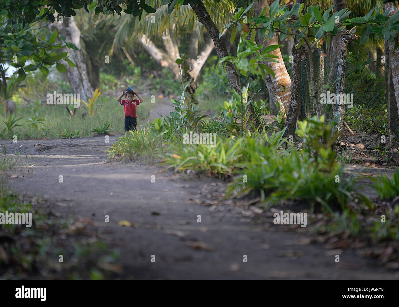 Ein kleiner Junge steht auf einen Sandweg der costaricanischen Karibik Stadt der Pacuare. Stockfoto