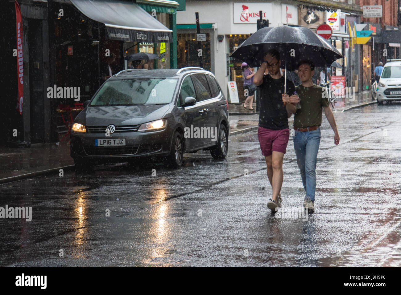 Soho, London, UK. 2. Juni 2017. Zwei Männer teilen einen Regenschirm als einer der Gewitter vorhergesagt durch die Met Office Pässe über Old Compton Street in Soho, London. Bildnachweis: Paul Davey/Alamy Live-Nachrichten Stockfoto