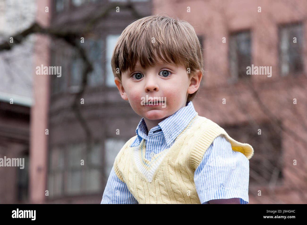Gut gekleidete 3 - jährigen Jungen vor Backsteinbauten in der Stadt Stockfoto