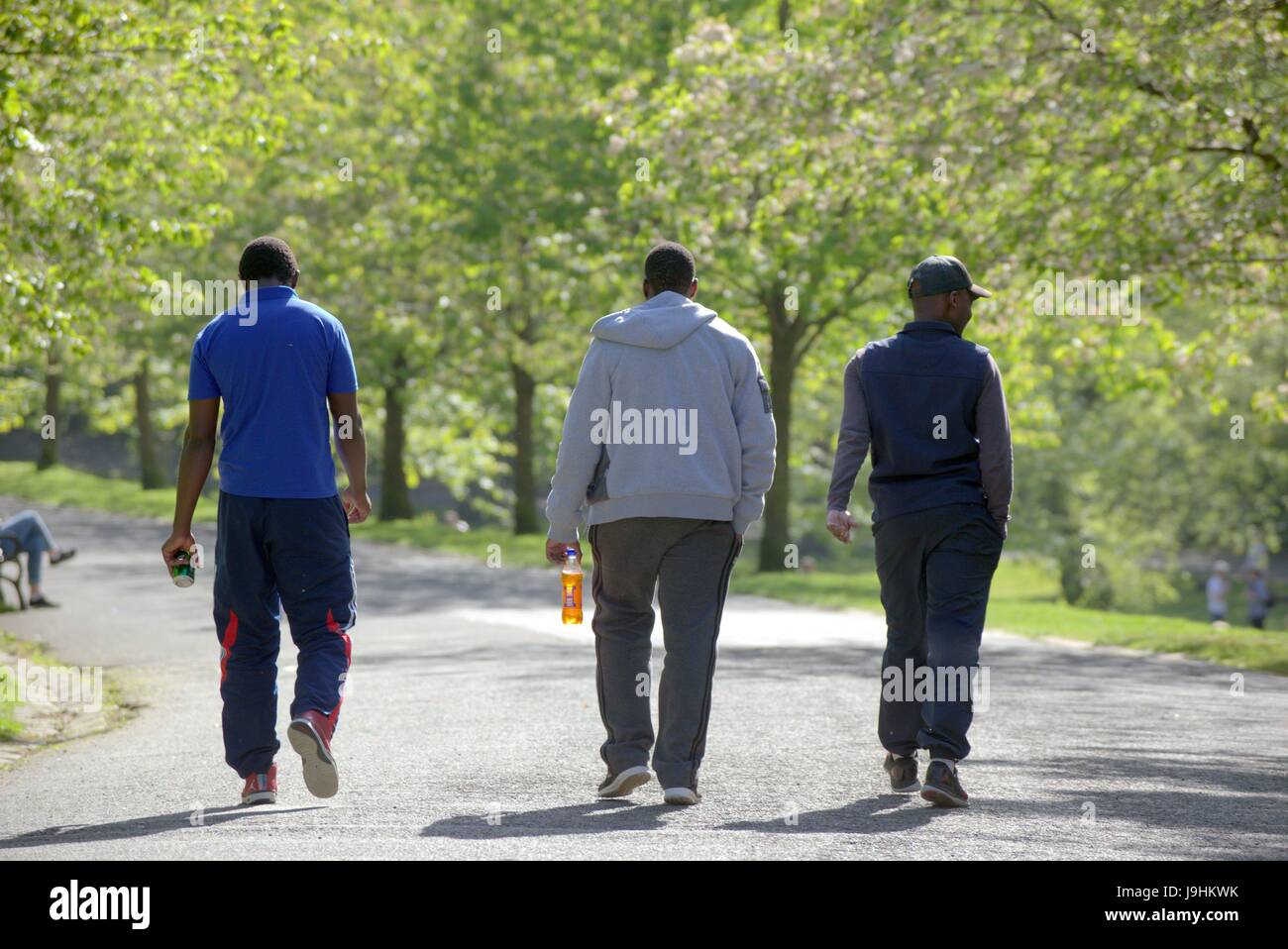 Glasgow Kelvingrove Park Szenen drei schwarze Männer mit Irn-Bru-Flasche Stockfoto