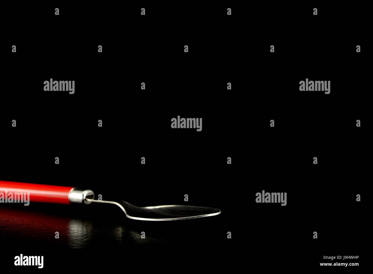 Roten behandelt Löffel auf einem schwarzen Hintergrund reflektiert Stockfoto