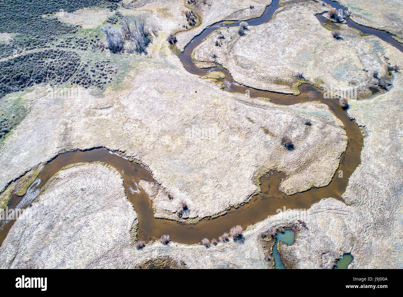 Illinois Fluß schlängelt sich durch Arapaho National Wildlife Refuge, North Park in der Nähe von Walden, Colorado, Vorfrühling Luftbild Stockfoto