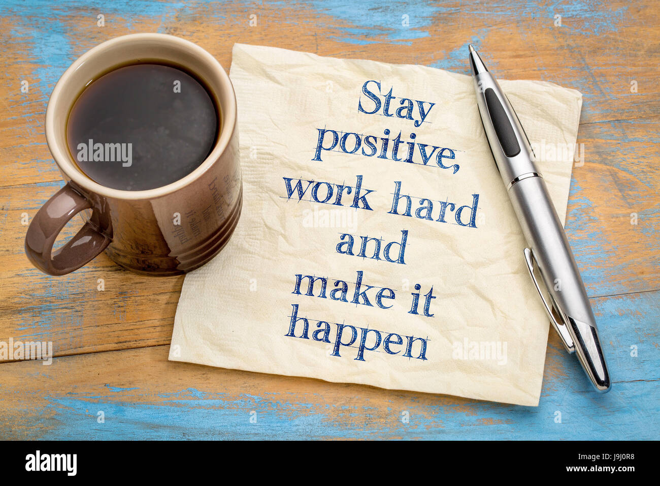 Bleiben Sie positiv, arbeiten hart und machen es möglich - motivierende Handschrift auf einer Serviette mit einer Tasse Kaffee Stockfoto