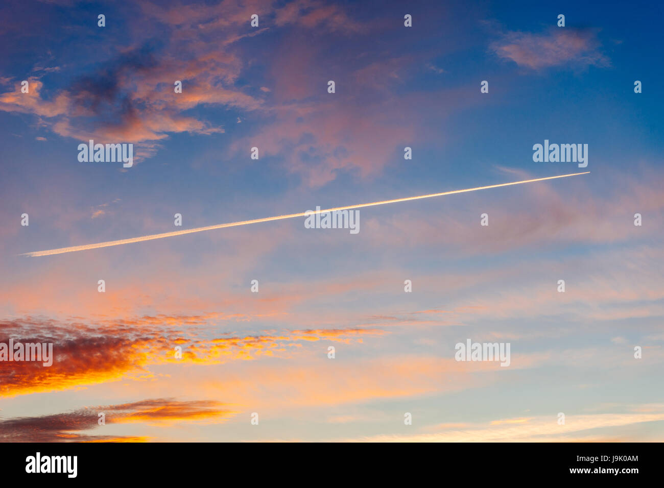 Spur von Flugzeugen in den dramatischen Himmel bei Sonnenuntergang. Kondensstreifen von Airline Kraftstoff in den Abend Wolkengebilde Stockfoto