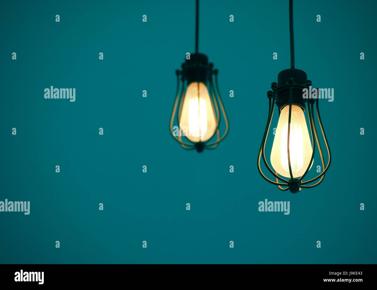 Beleuchtet, hängenden Glühbirnen auf blauen einfarbigen Hintergrund mit Freitext-Raum Stockfoto