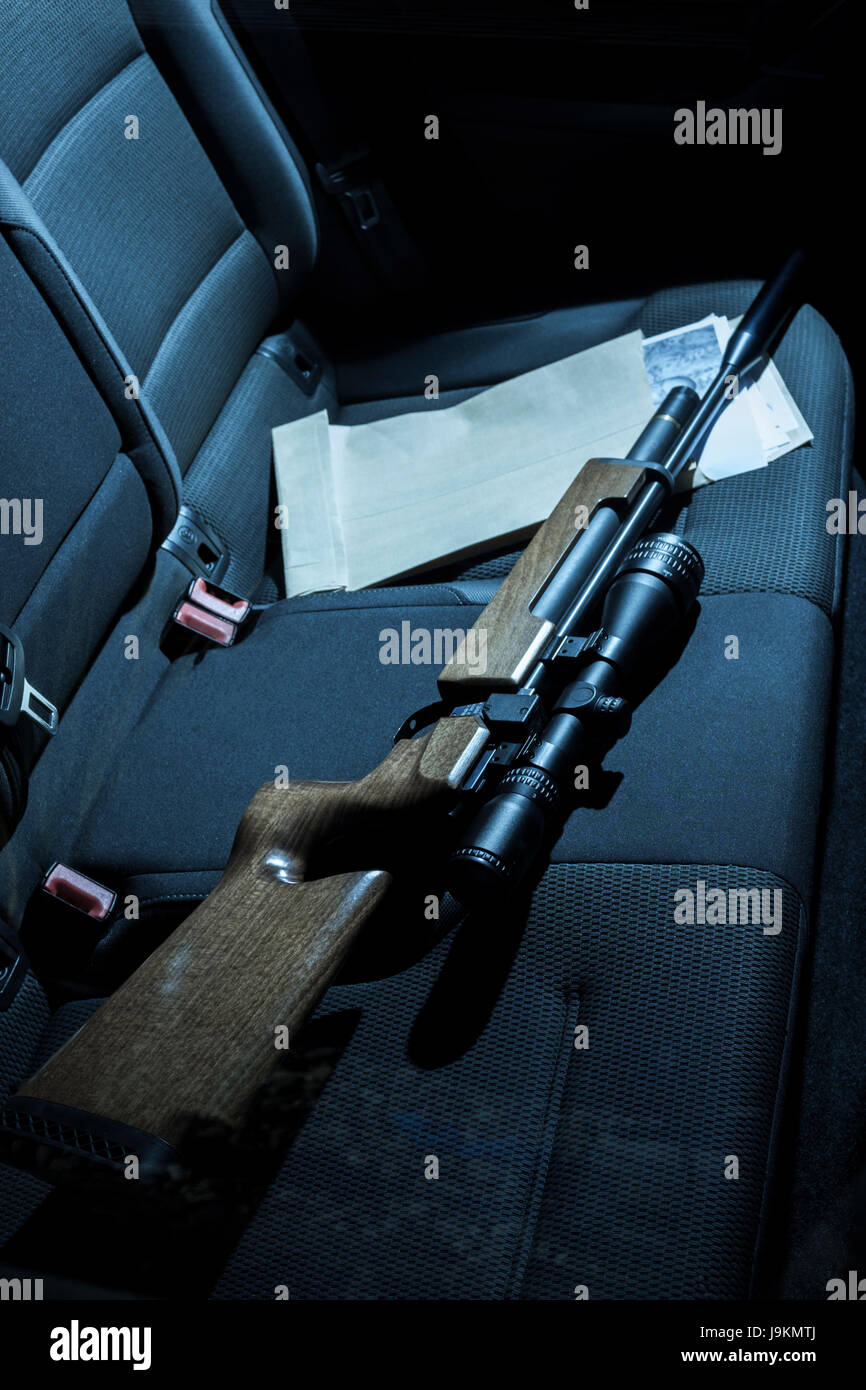 Eine Pistole und Fotos auf dem Rücksitz eines Autos. Stockfoto