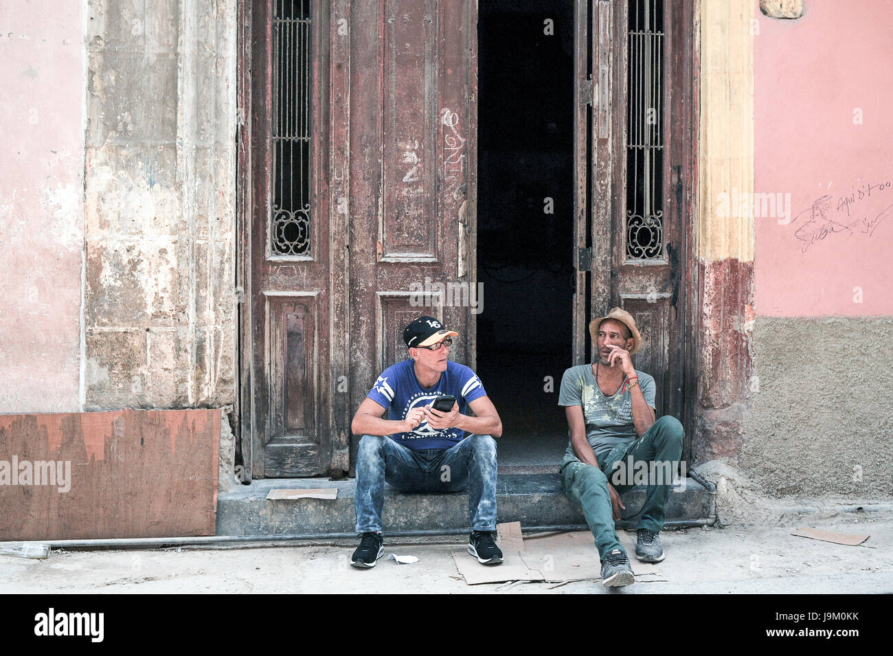 Lokalen Kubaner sitzt und raucht Zigarre vor Haustür in Havanna, Kuba Stockfoto