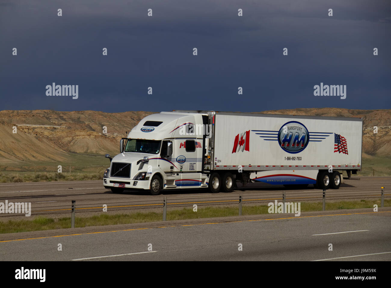 Eine weiße Volvo Lastwagen zieht ein weißes "HM" Trailer auf einen US-Autobahn. Stockfoto