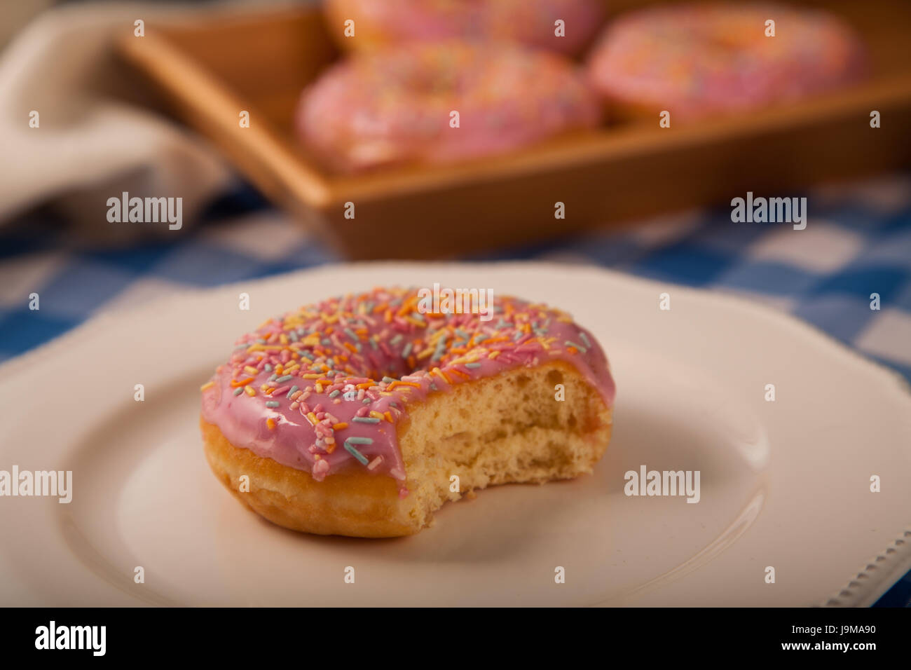 Rosa Donut auf einem Teller mit Biss herausgenommen Stockfoto
