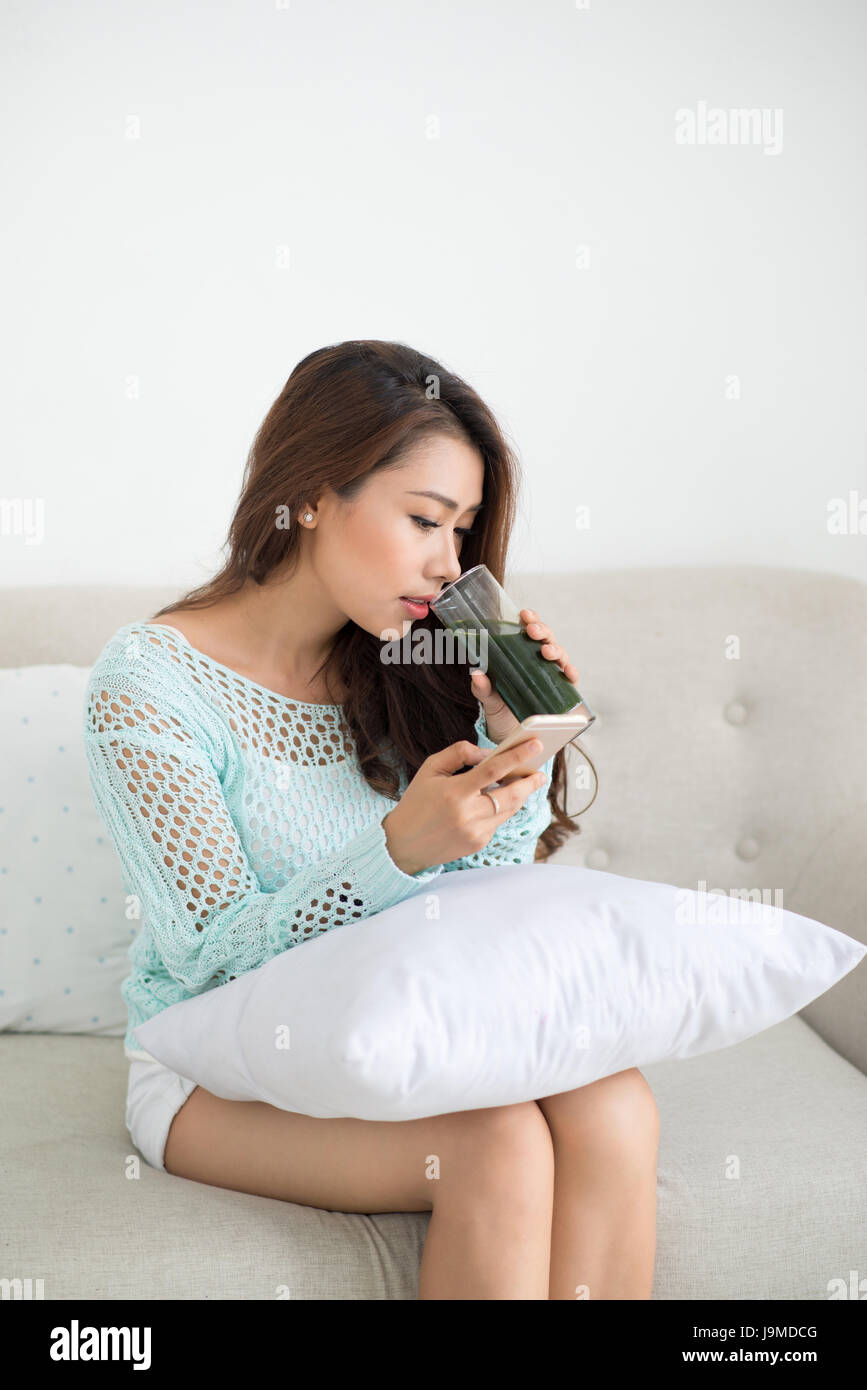 Asiatin mit Smartphone auf couch Stockfoto