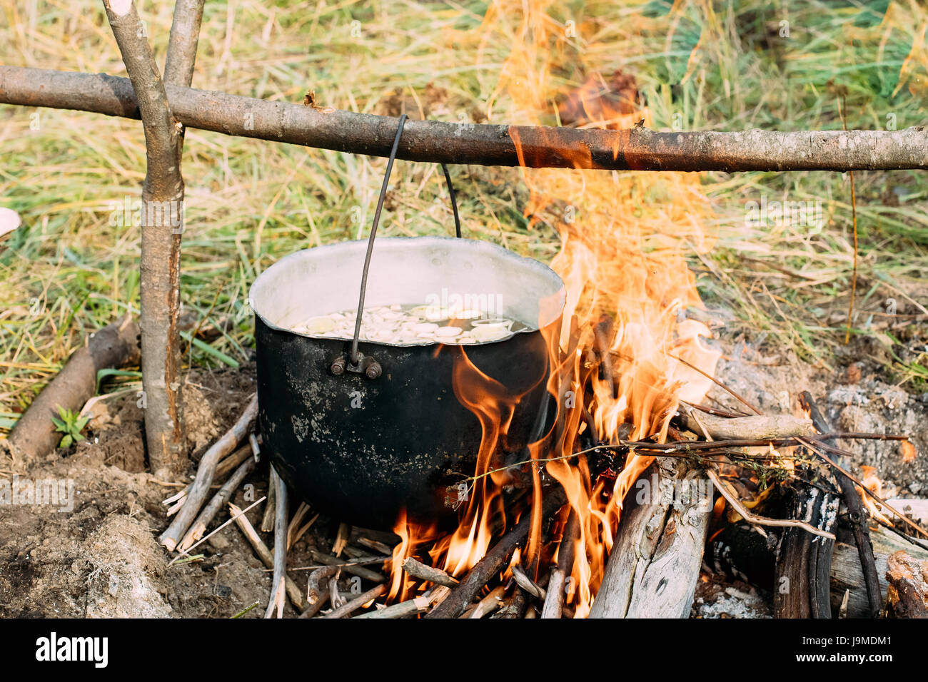 Alten Retro-Camp Topf abgekochtes Wasser für die Zubereitung der Suppe auf einem Feuer im Wald. Flamme Feuer Lagerfeuer am Sommertag. Stockfoto