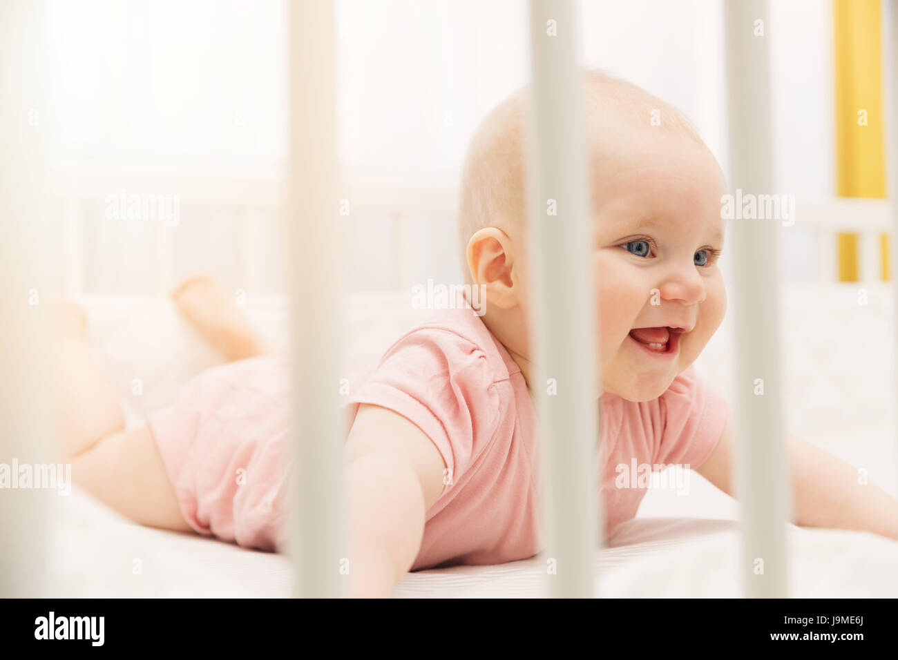 niedliche glückliches Babymädchen spielen in Krippe Stockfoto