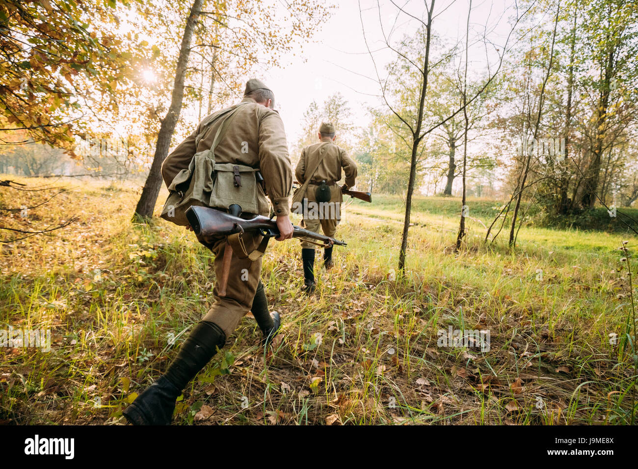 Zwei Re-enactment gekleidet als russische sowjetische Rote Armeesoldaten des zweiten Weltkriegs versteckt laufen auf feindliche Stellungen im Herbst Wald während der historischen Reena Stockfoto