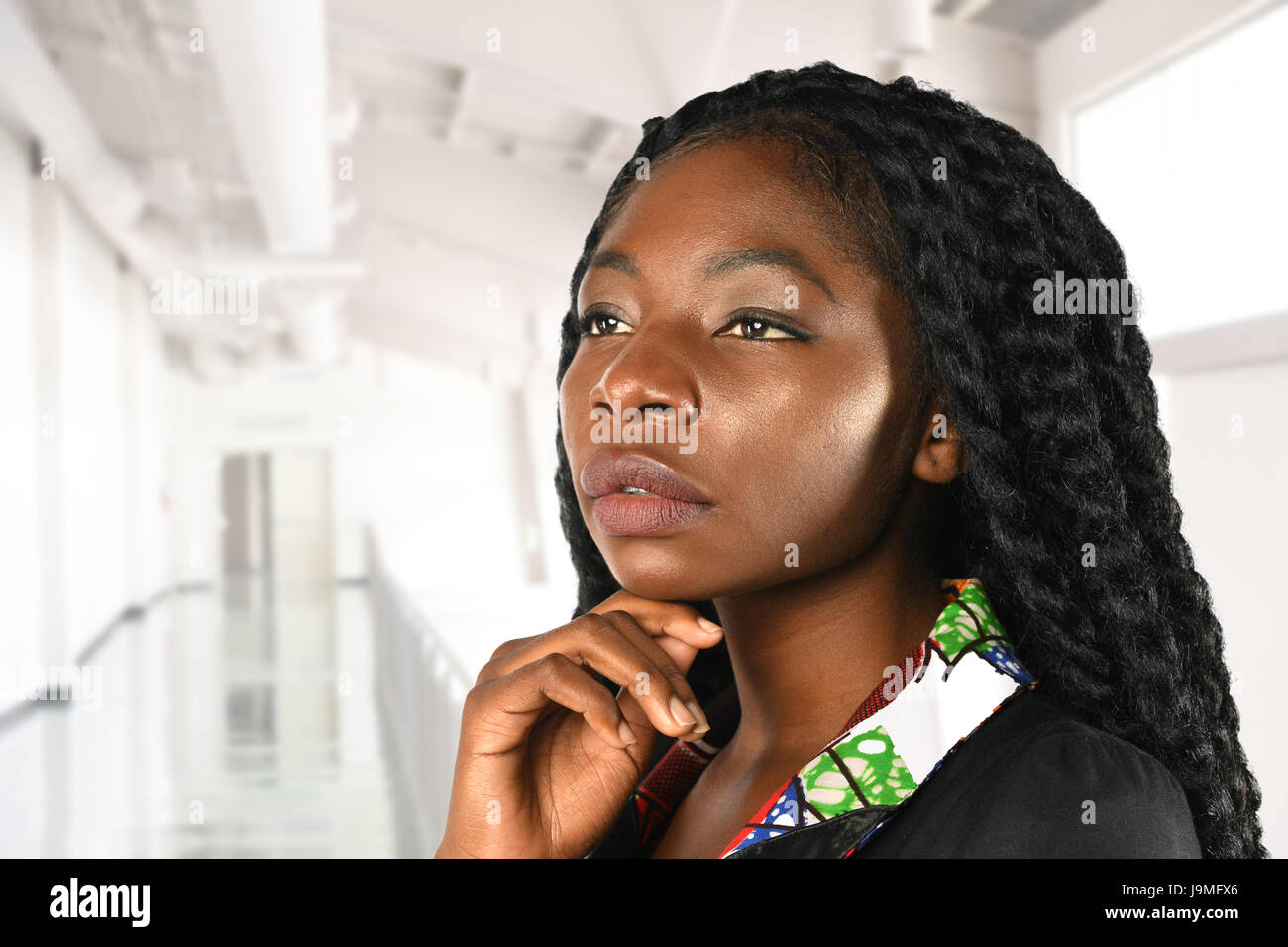 Porträt der schönen afroamerikanischen Geschäftsfrau mit Hand am Kinn in Bürogebäude Stockfoto