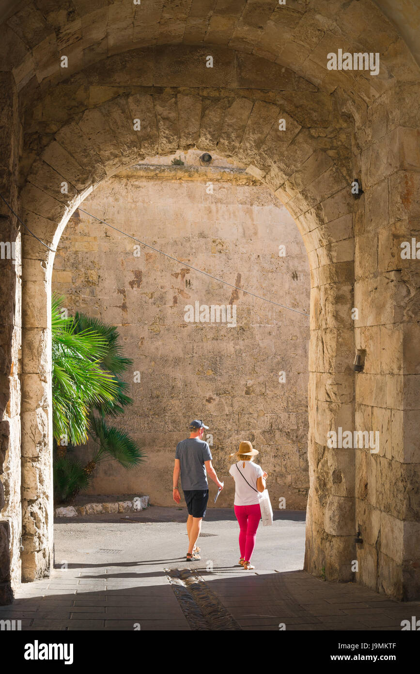 Reifes Paar reist, Blick auf ein Paar mittleren Alters im Urlaub, das durch das Tor unter dem Elephantenturm, Castello Gegend, Cagliari, Sardinien, geht. Stockfoto