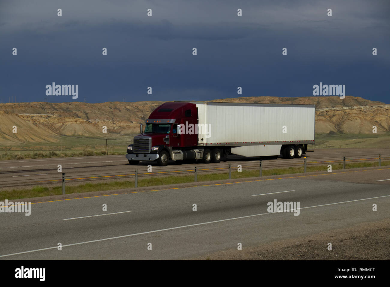 Einen roten oder braunen Lastwagen zieht einem weißen Anhänger entlang einer ländlichen uns Interstate. Alle Abzeichen und Embleme wurden entfernt. Stockfoto