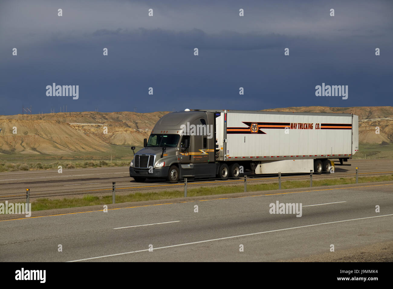 Gold Freightliner Semi-Lkw Ziehen einer weiße "Kann Trucking Co." Trailer entlang einer ländlichen uns Interstate. Stockfoto