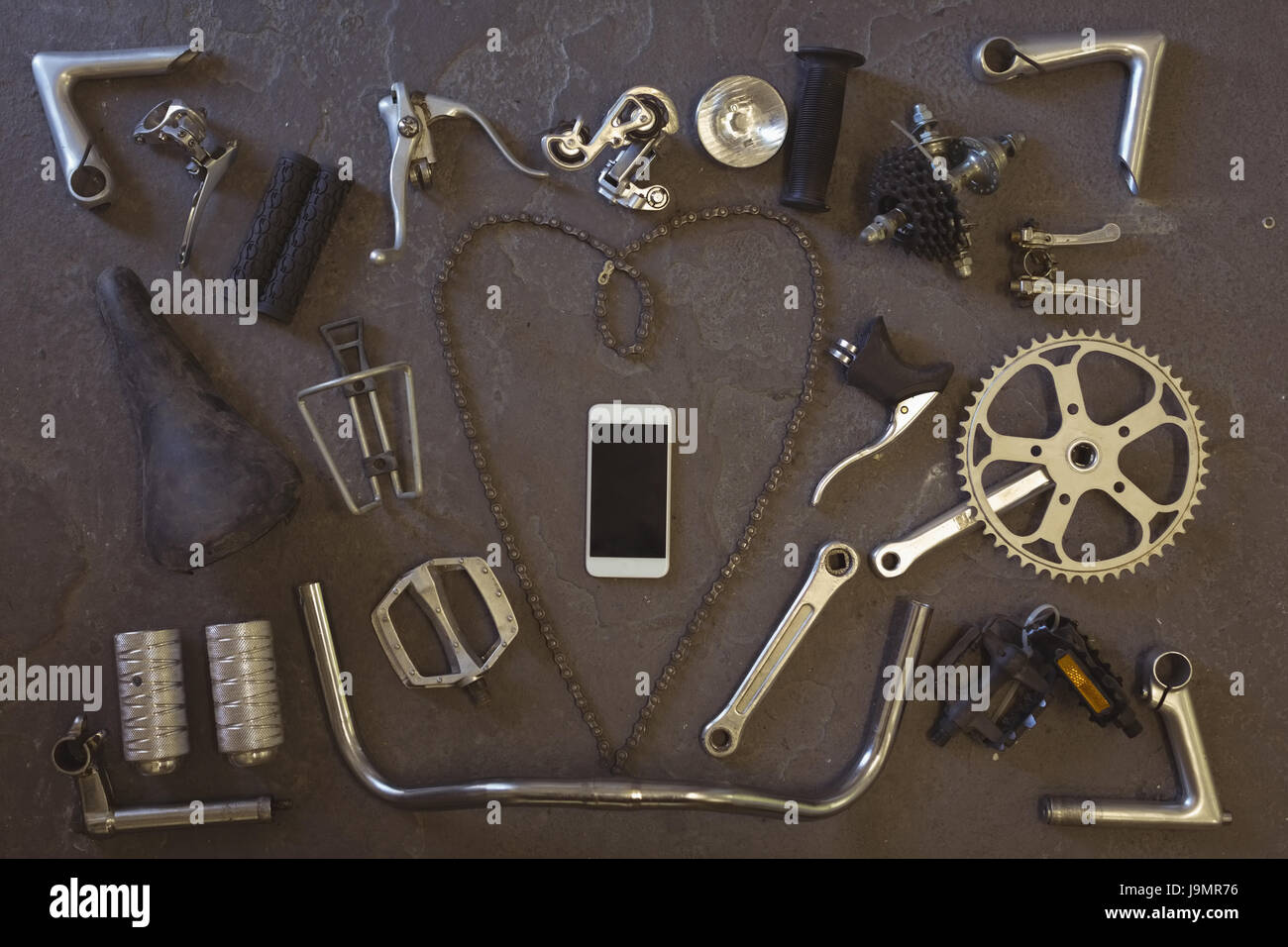 Draufsicht des Mobiltelefons inmitten Fahrradteile im Stock am workshop Stockfoto