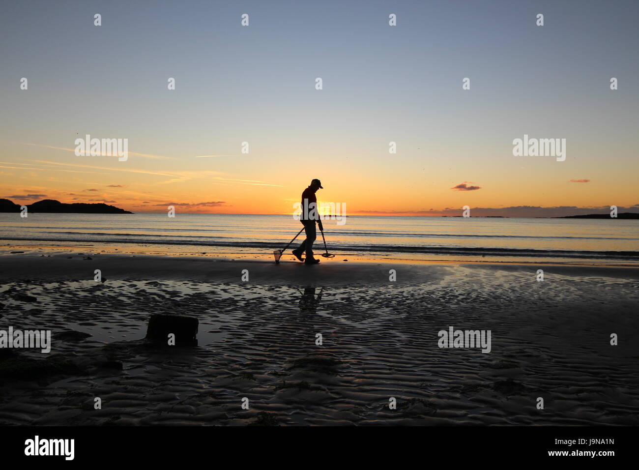 Metall Schatzsucher bei Sonnenuntergang am Strand auf der Suche nach Schatz Stockfoto