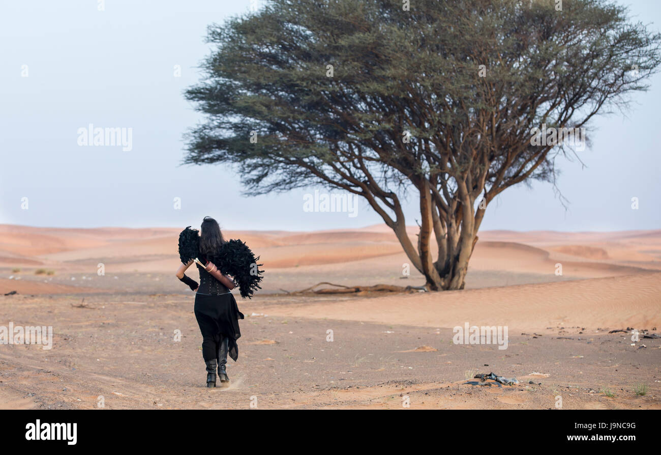 junge Frau mit einem Bogen und Arrors in einer Wüste in der Nähe von Dubai Stockfoto