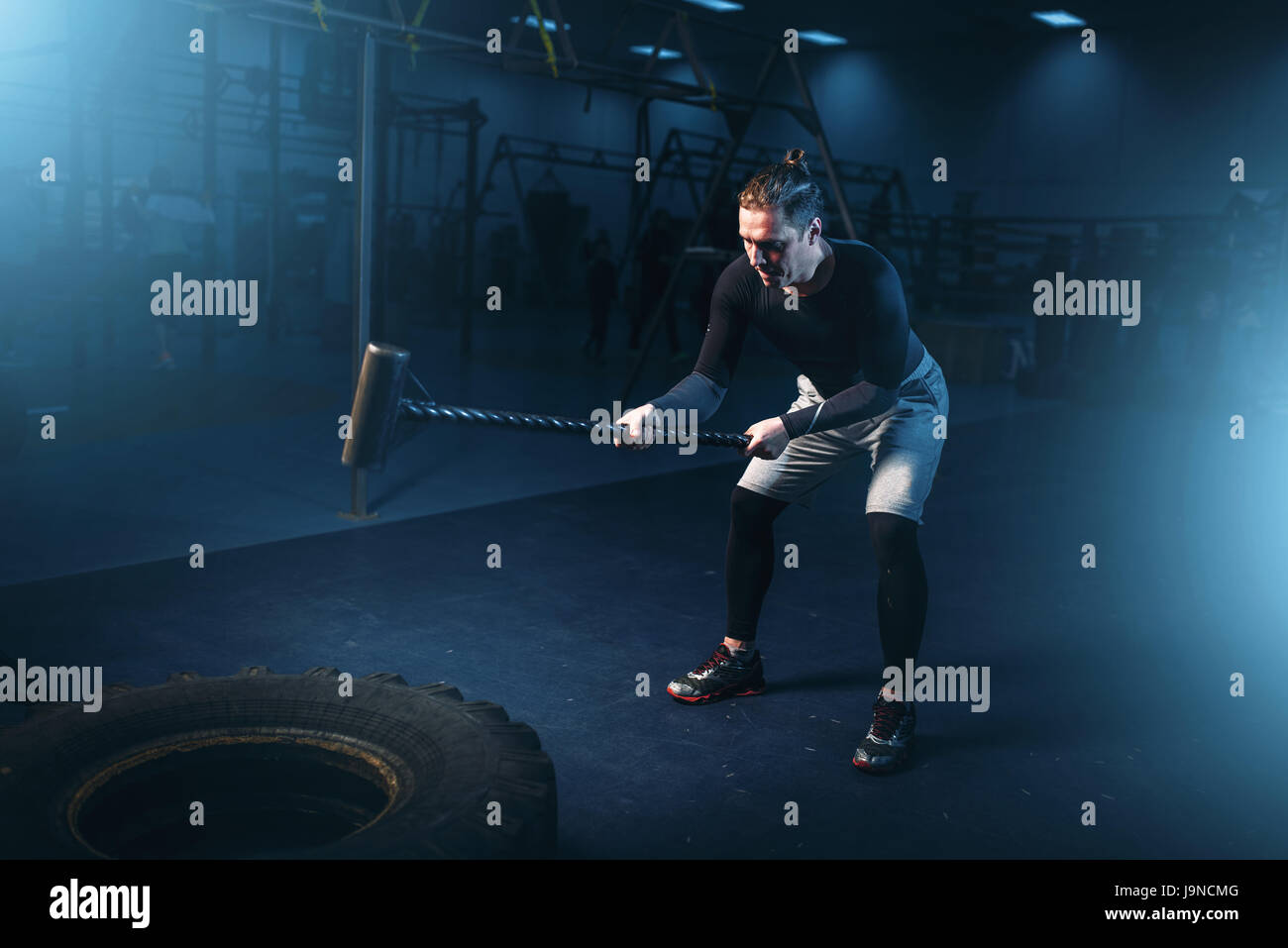 Training im Fitness-Studio, Mann mit Vorschlaghammer Hits Reifen. Aktive Bewegung im Sportverein Stockfoto