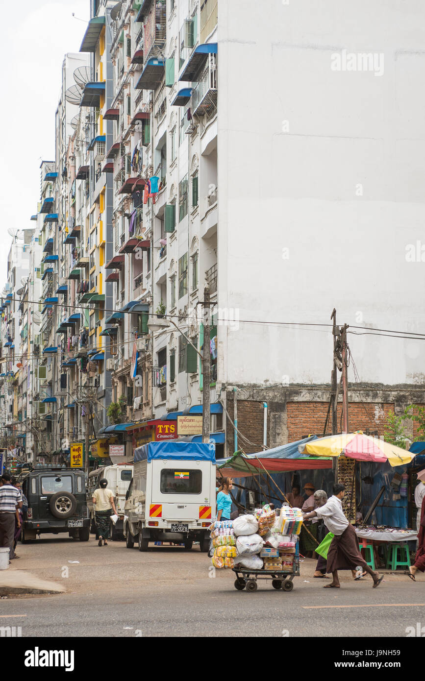 Ein Mann schiebt einen Wagen durch eine Straße in Yangon, Myanmar Stockfoto