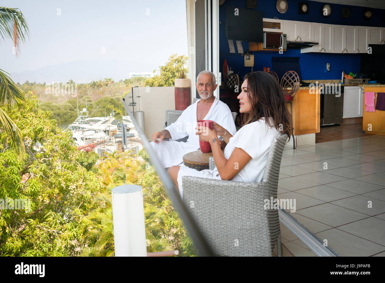Paar, sitzen auf dem Balkon mit Blick auf den Yachthafen von Nuevo Vallarta, Nayarit, Mexiko Stockfoto