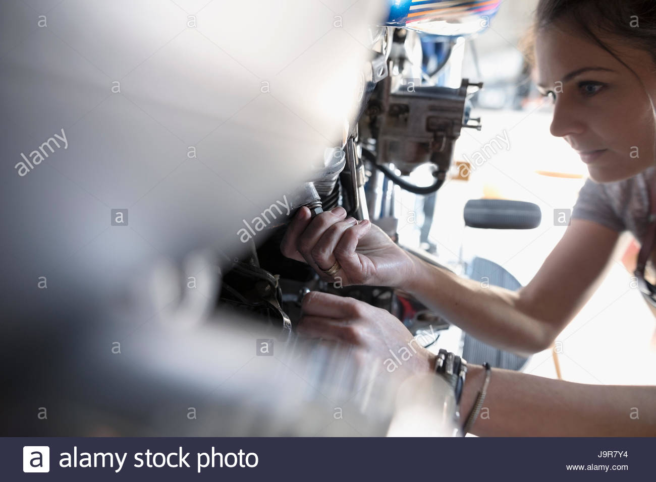 Weibliche Motorrad-Mechaniker Befestigung Motorrad in Autowerkstatt Stockfoto