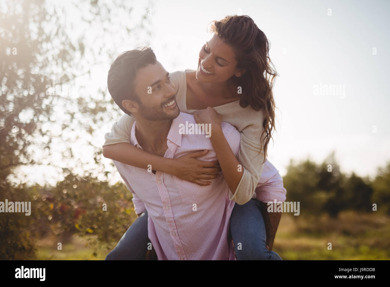 Lächelnde junge Frau am Bauernhof im sonnigen Tag Huckepack Stockfoto