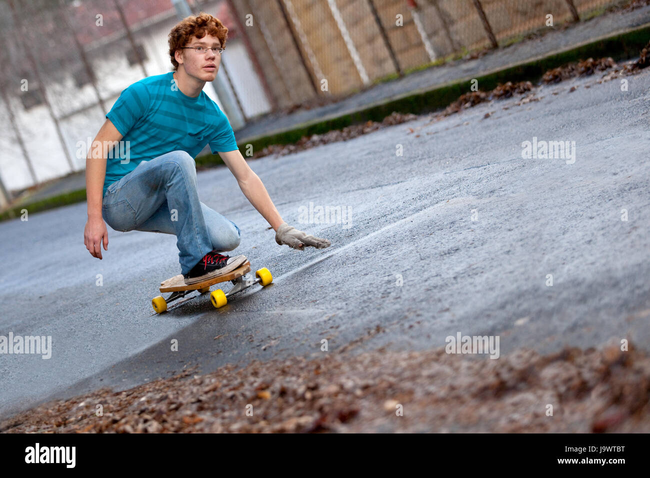 Teenager Reiten eine Longboard Downhill auf einer nassen Straße Stockfoto