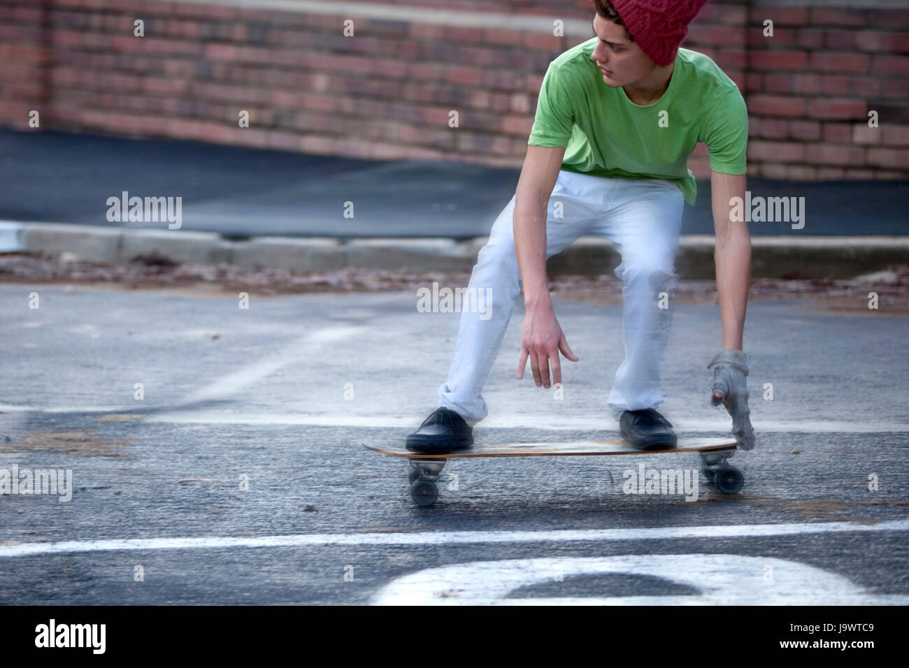 Teenager Reiten eine Longboard auf einer nassen Straße Stockfoto