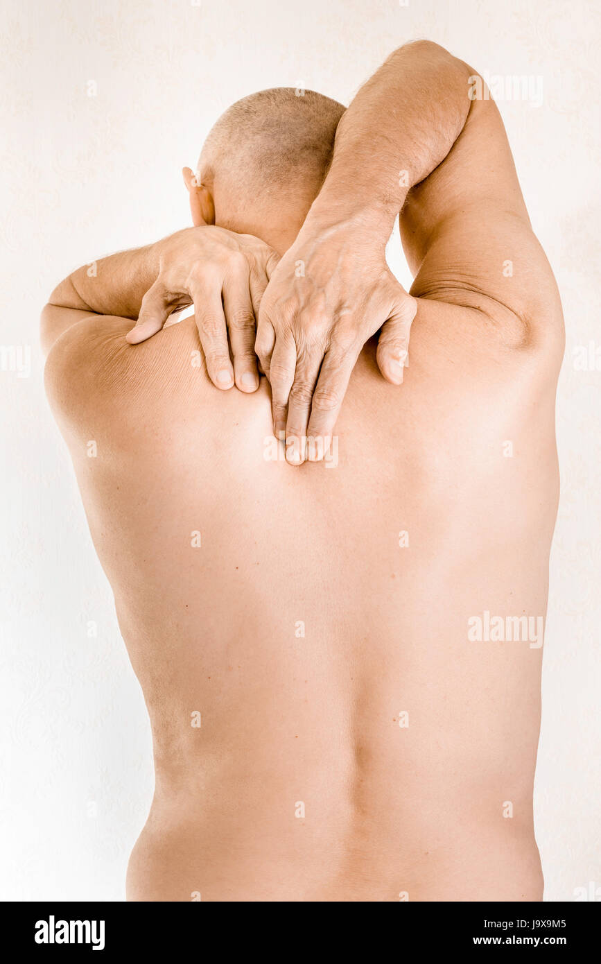 Mann massiert den oberen Rücken, zwischen den Schultern, weil ein Brustwirbel Schmerz durch eine Verschiebung von einem dorsalen Wirbel reiben auf einen Nerv Stockfoto