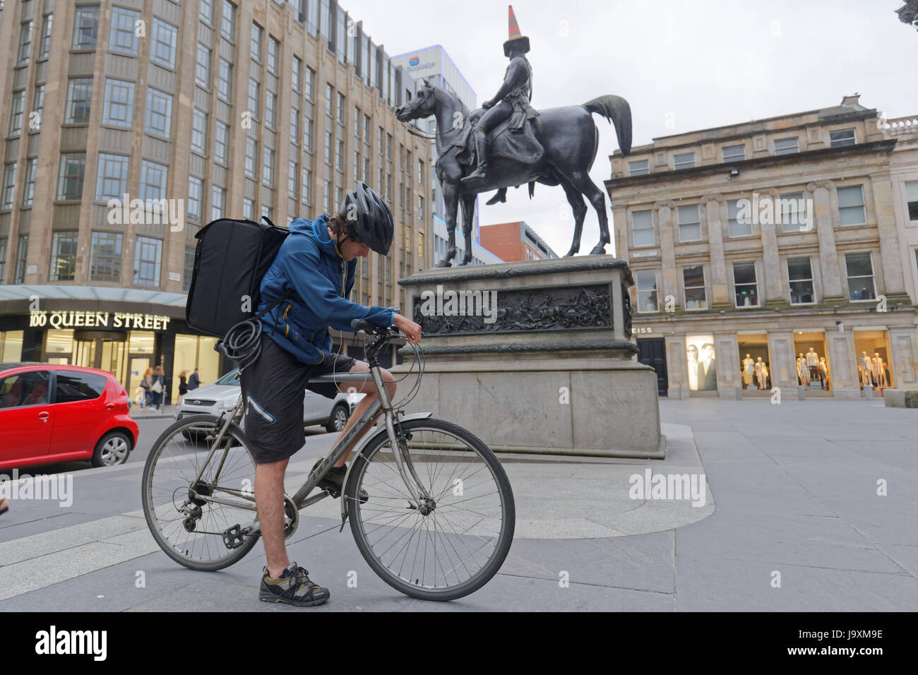 Deliveroo Uber Auslieferungsfahrer Biker Radfahrer auf der Straße nach Glasgow im Hinblick auf die Kegel Kopf Herzog von Wellington statue Stockfoto