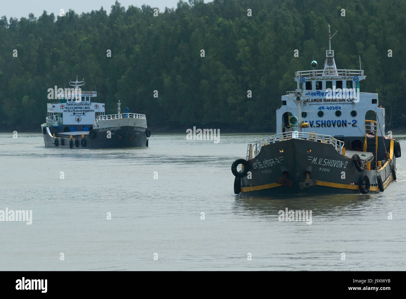 Frachtschiffe, die nah am Ufer des Shibsha Flusses in den Sundarbans trotz ökologischen Risiken navigieren. Satkhira, Bangladesch Stockfoto