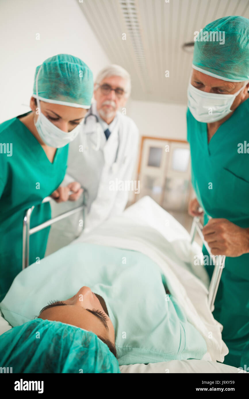 Patienten, die auf einem medizinischen Bett neben Ärzten im Krankenhausflur liegend Stockfoto