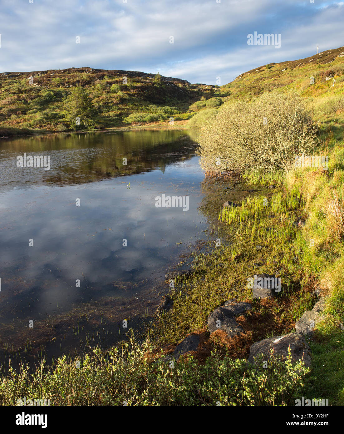 Kleines Loch auf der Insel Colonsay in Schottland aufgenommen in den frühen Morgenstunden mit Reflexion der Wolken im Wasser Stockfoto