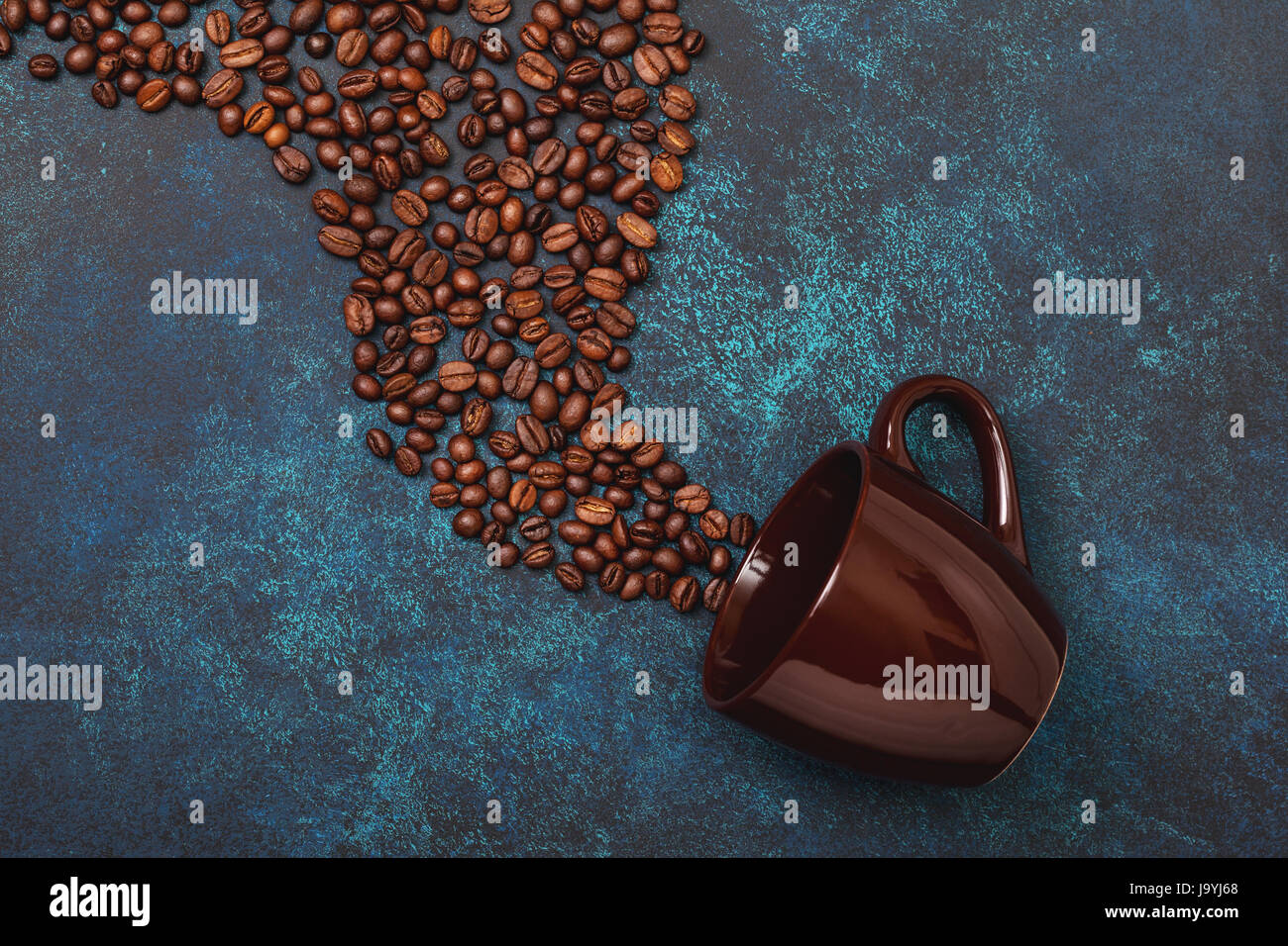 Kaffeebohnen und Becher auf konkreten Hintergrund. Ansicht von oben Stockfoto