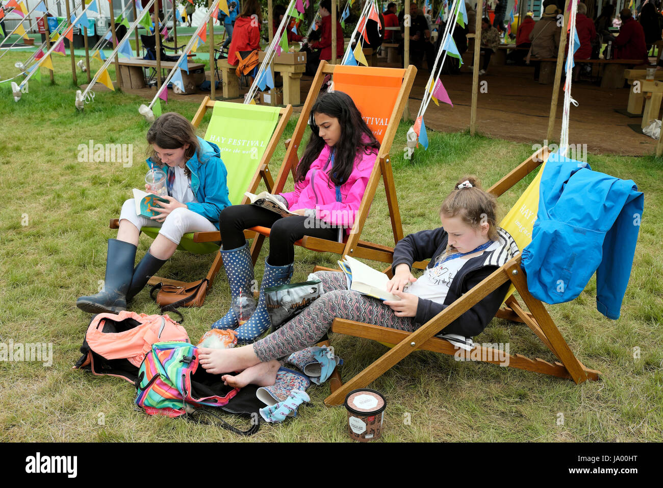 Eine Gruppe von jugendlichen Mädchen Freunde Lesen von Büchern sitzen auf Liegestühlen auf dem Hay Festival Website Hay-on-Wye, Wales UK KATHY DEWITT Stockfoto